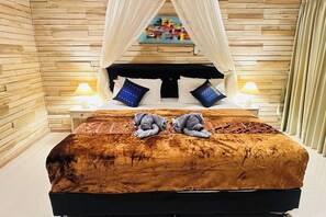 A bed with a canopy, two bedside lamps, and a colorful artwork above the bed. - Villa Aris 1 Bali (Munggu)