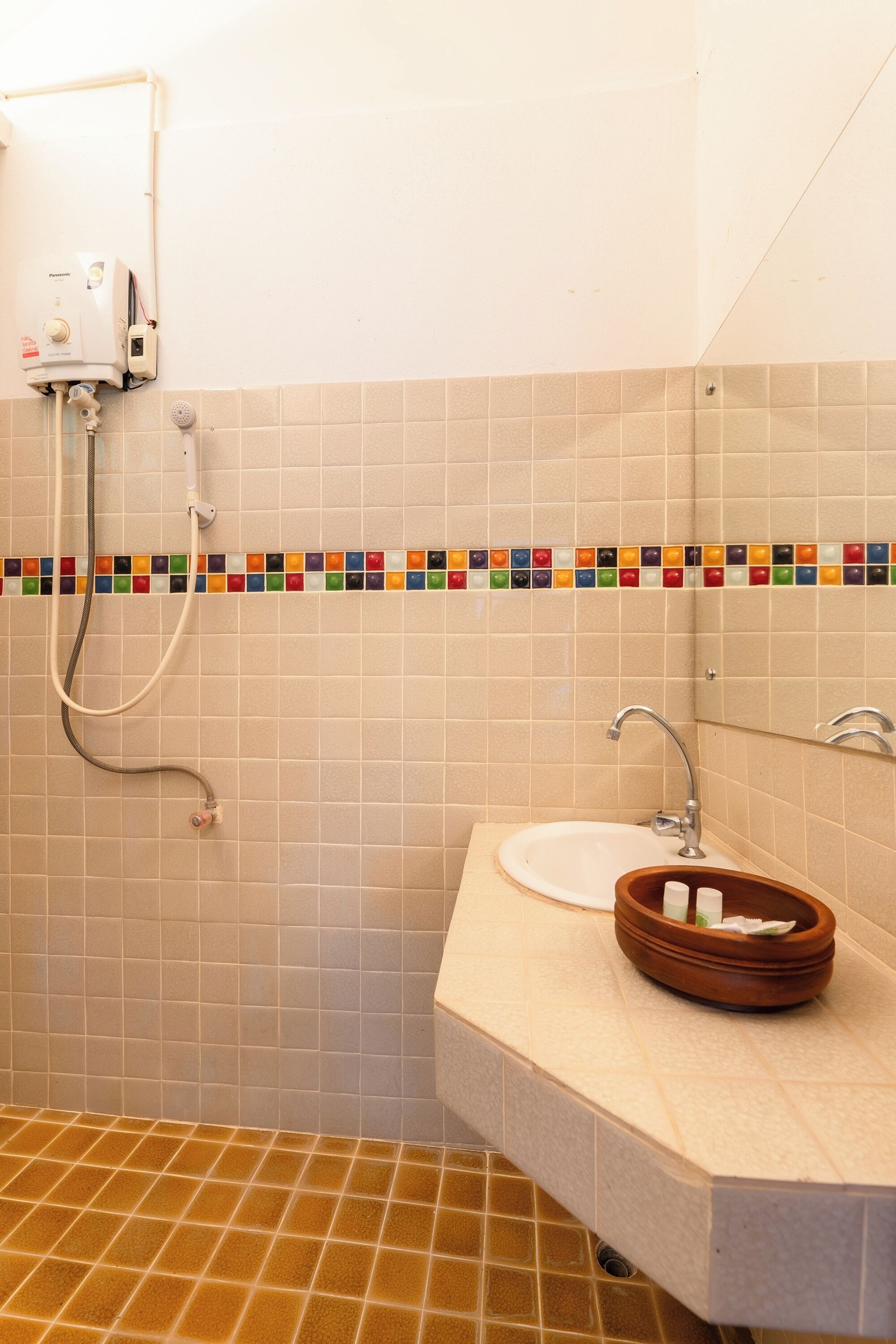 A bathroom with a white sink, a mirror, and a shower with a handheld showerhead.