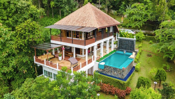 Una casa a due piani con piscina, immersa nel verde.