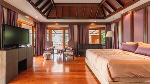 Una camera d'albergo spaziosa con un ampio letto, una TV a schermo piatto, un'area salotto con poltrone e ampie finestre con vista sull'esterno.