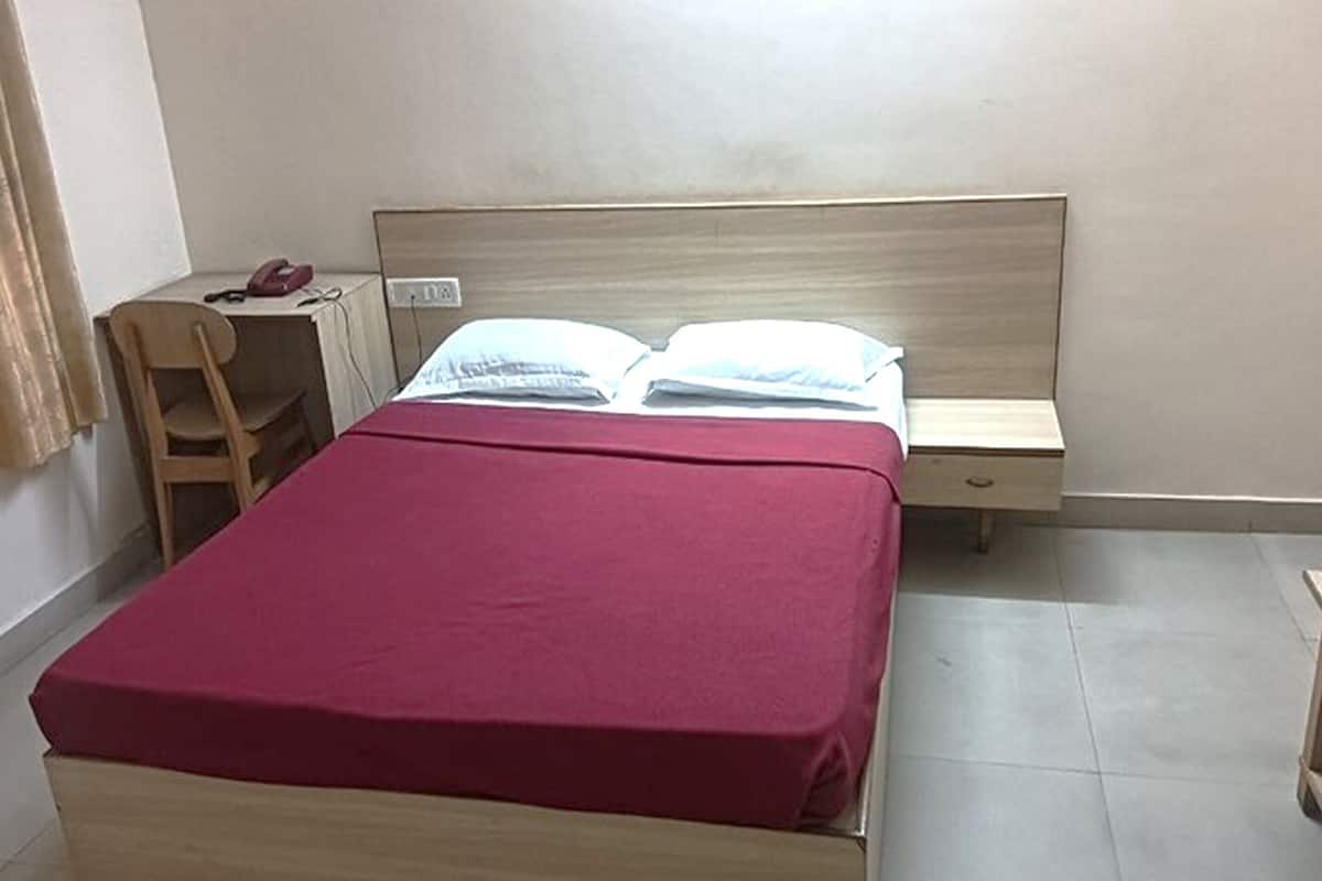 A bedroom with a bed, a desk, and a chair.