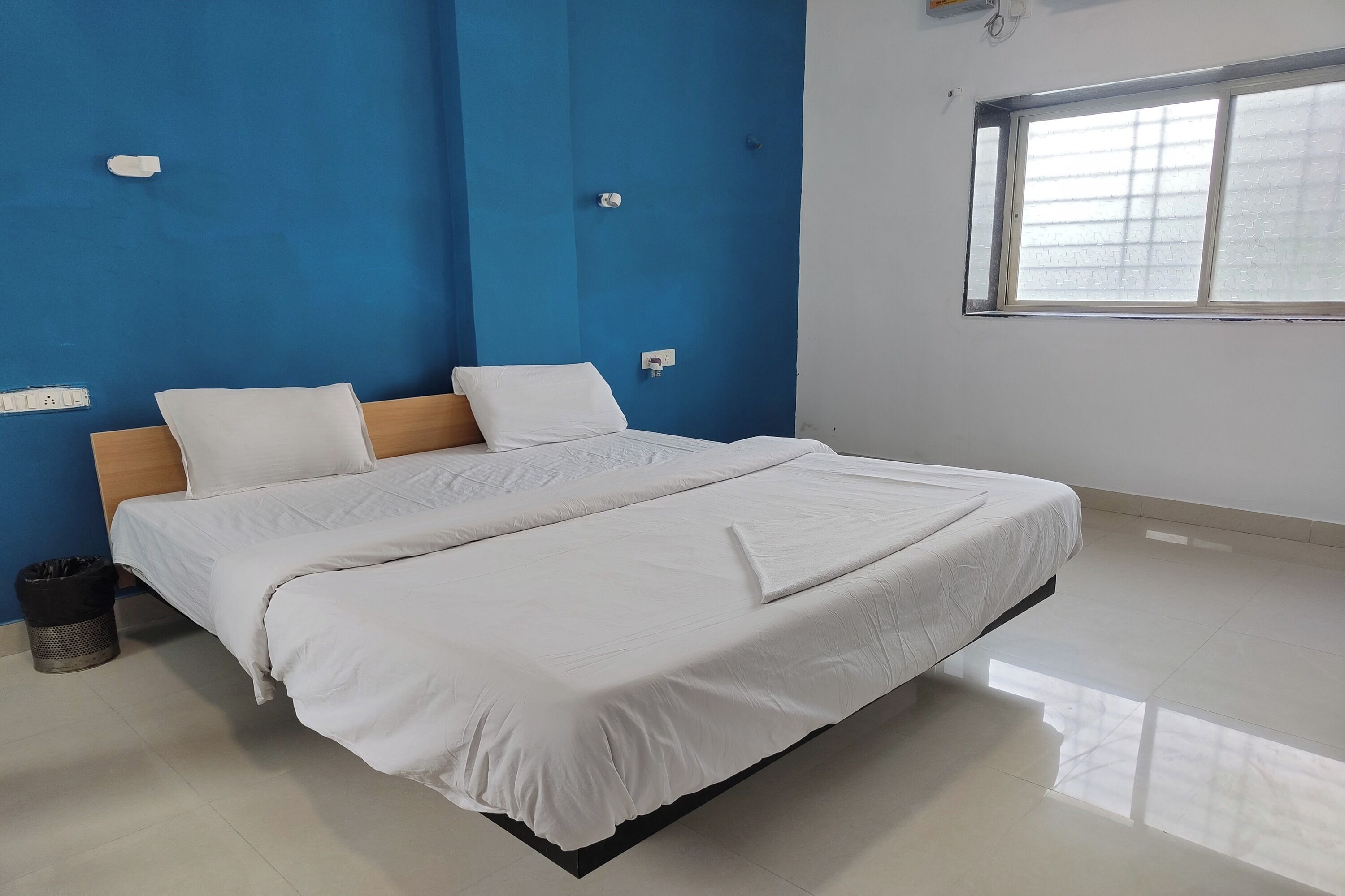 Un dormitorio con cama, ventana y pared azul.