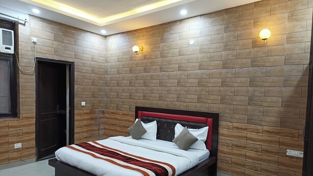 A bedroom with a bed, wooden wall paneling, and recessed ceiling lighting. - Swastika Homes Near Wave City Center Noida (Noida)