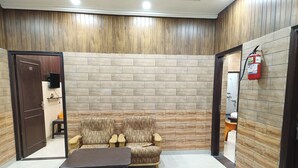 A room with a sofa, a table, and a fire extinguisher on the wall. - Swastika Homes Near Wave City Center Noida (Noida)