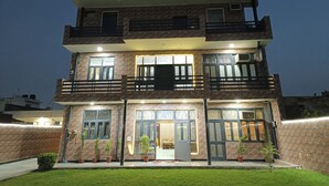 A multi-story building with a balcony, large windows, and potted plants. - Swastika Homes Near Wave City Center Noida (Noida)