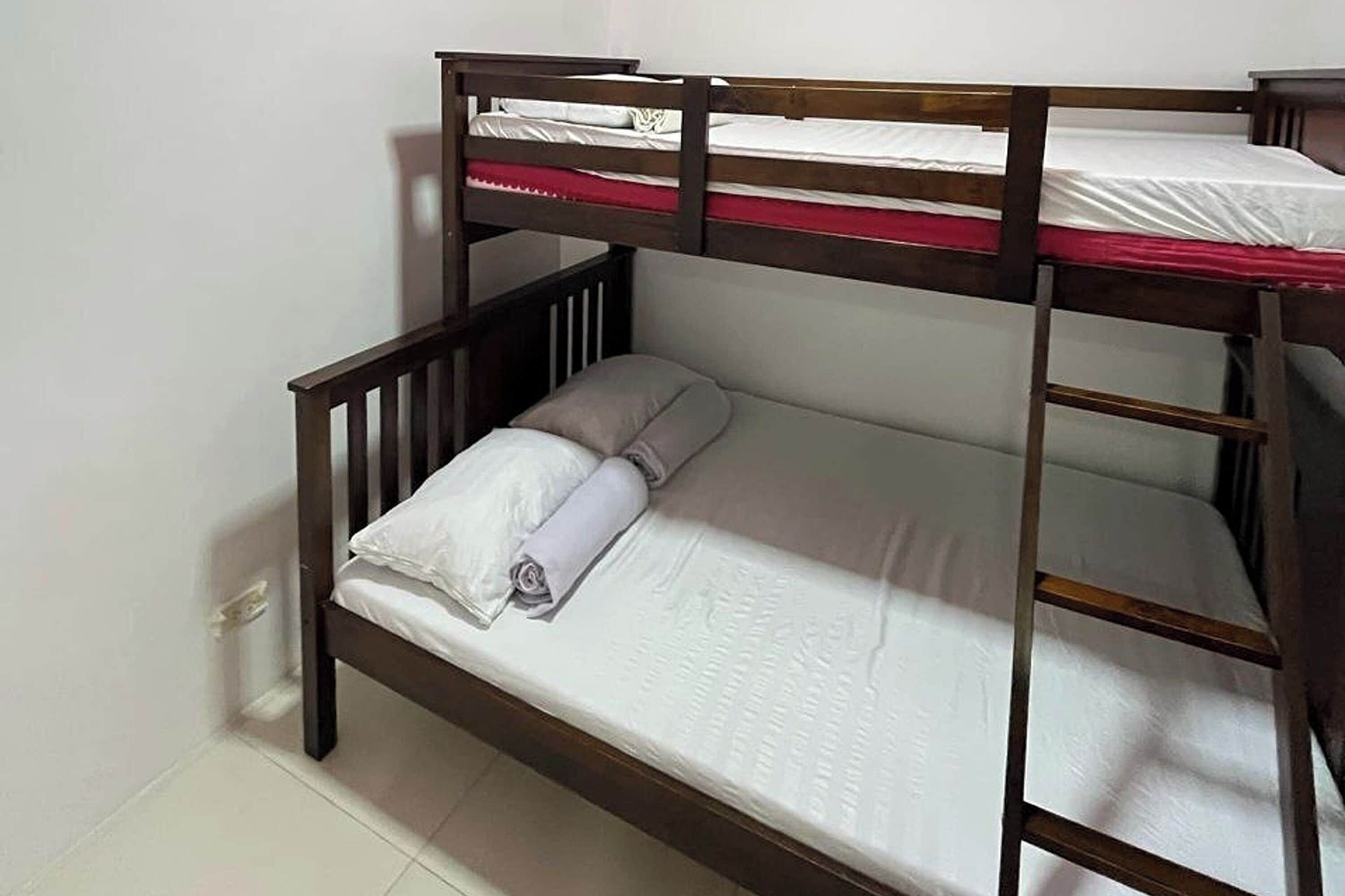 Una cama litera con estructura de madera y ropa blanca.