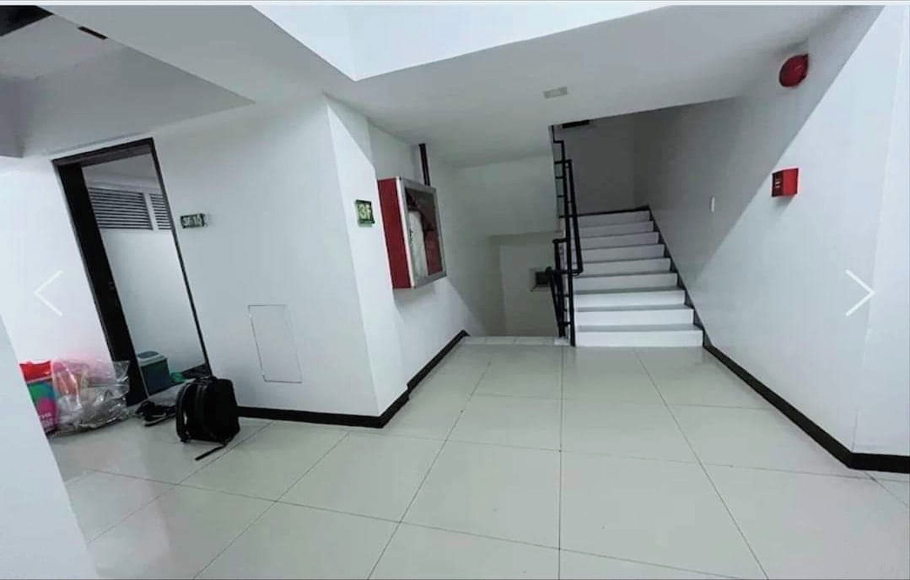 A clean, modern interior with a staircase, white walls, and a tiled floor.
