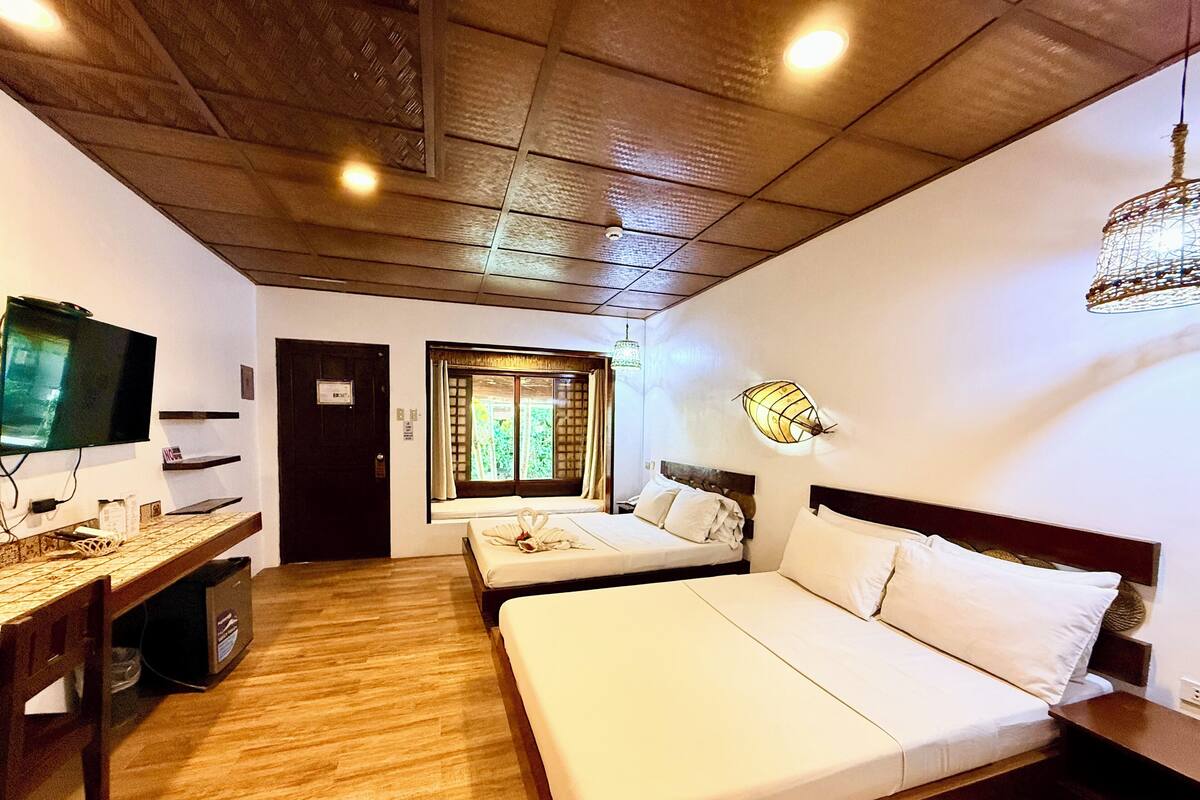 Une chambre d’hôtel avec deux lits, un bureau, une télévision et une fenêtre avec des rideaux.