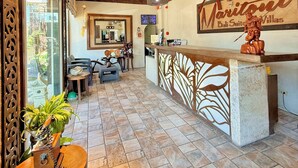 Un área de recepción con un mostrador de madera, un ventilador de techo y un cartel que dice 'Maritoni Bali Suites'.
