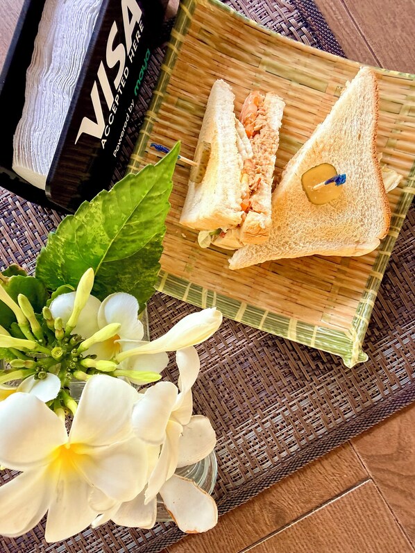 A sandwich on a woven mat, a Visa card, and a white flower. - Maritoni Bali Suites And Villas (Bauang)