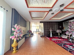 A hotel lobby with a wooden floor, a long reception desk, and a seating area with a patterned rug. - Villa Zahira & House 2 (Jambi)