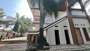 A modern building with a balcony, a tiled entrance, and surrounding greenery. - Villa Zahira & House 2 (Jambi)