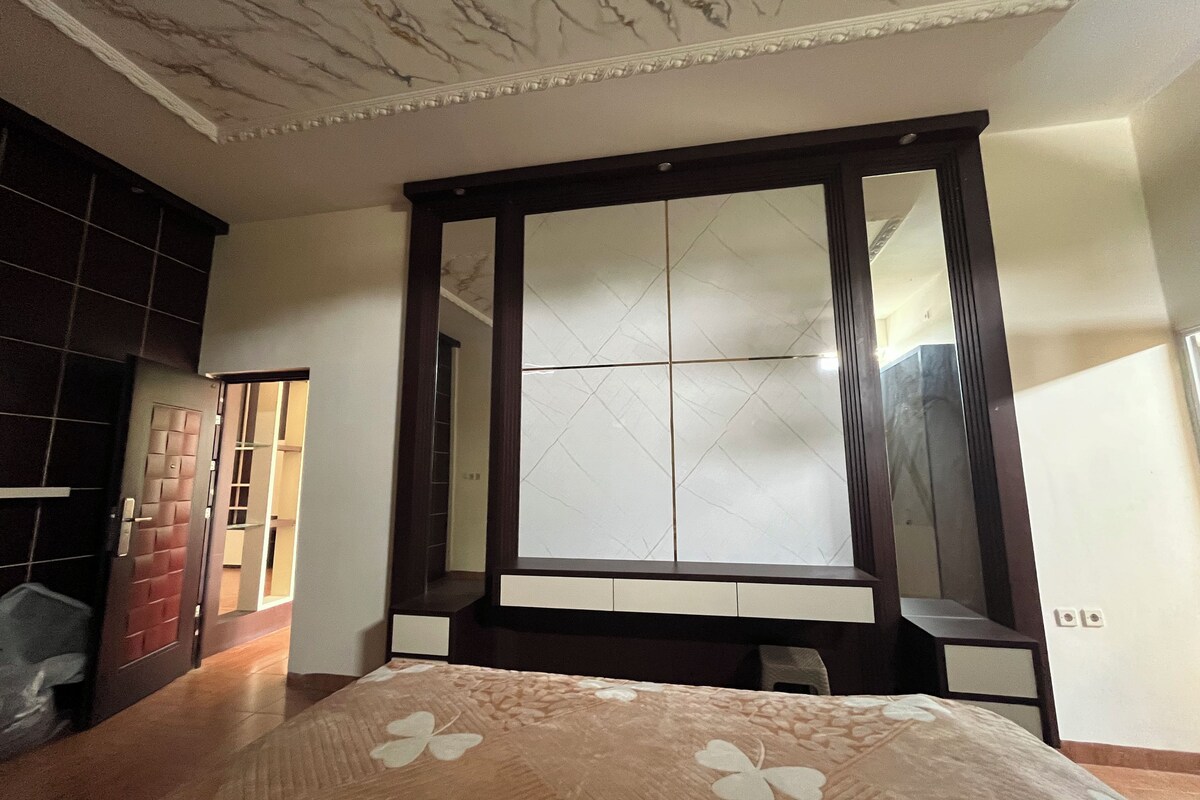 Un dormitorio con un armario grande, una cama con colcha estampada y un techo de mármol.