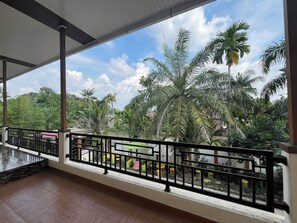 A balcony with a view of palm trees and a clear sky. - Villa Zahira & House 2 (Jambi)