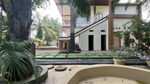A courtyard with a pool, palm trees, and a building with a balcony. - Villa Zahira & House 2 (Jambi)