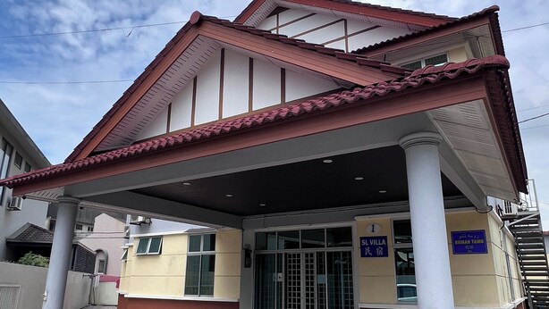 A building with a covered entrance, a sign indicating it is a public facility, and a clear sky in the background. - SL Villa Guesthouse, Kuantan (Kuantan)
