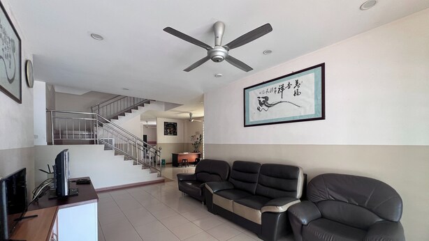 A spacious living area with a sofa, a television, and a staircase leading to an upper floor. - SL Villa Guesthouse, Kuantan (Kuantan)