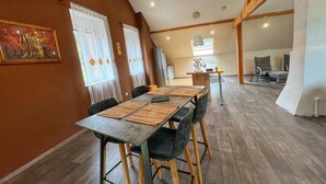 A dining area with a long table, chairs, and a kitchen in the background. - Spacious loft in the forest (Bining)