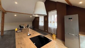 A modern kitchen with a central island, built-in oven, and a stainless steel refrigerator. - Spacious loft in the forest (Bining)