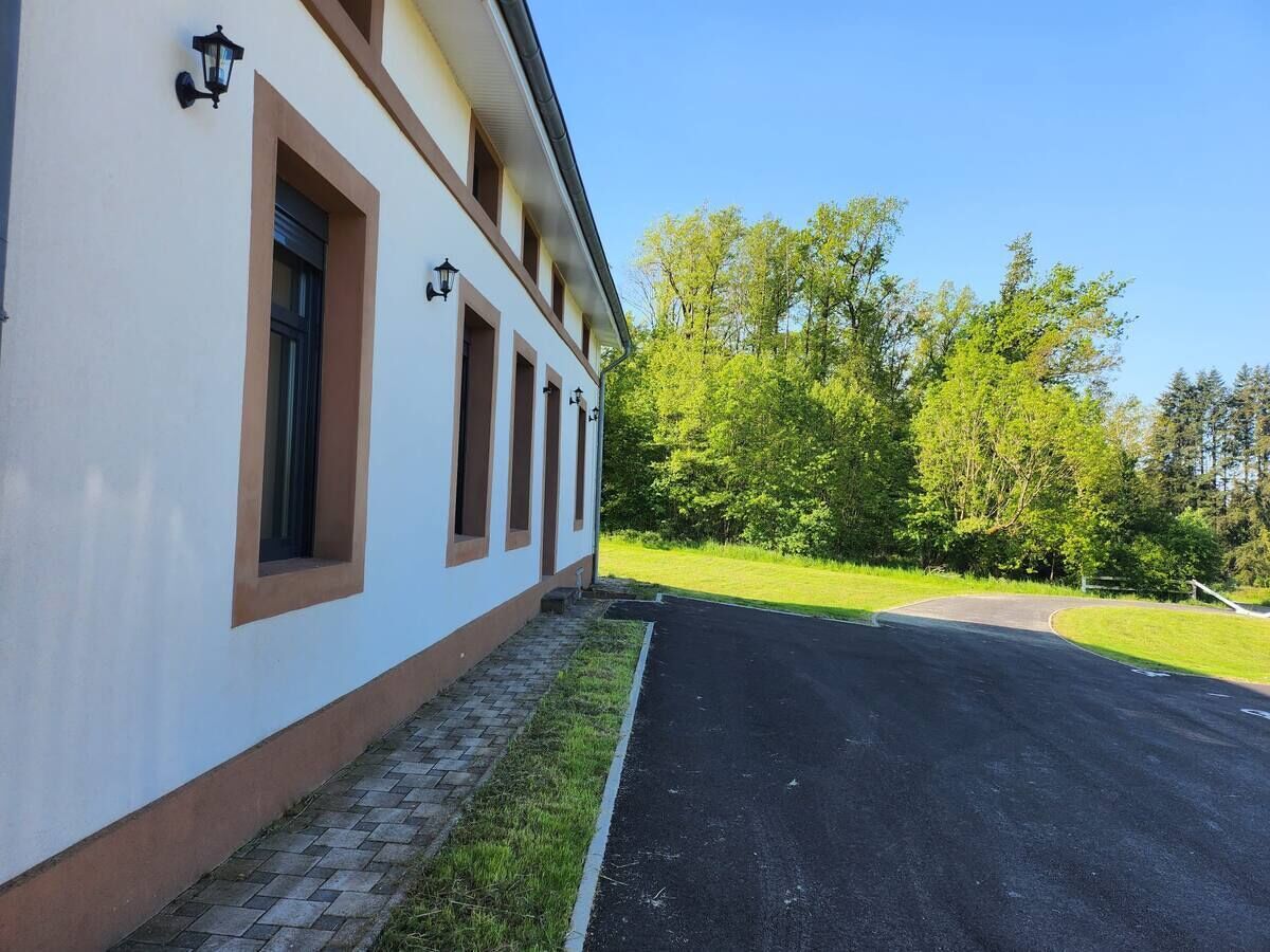 A building with a paved driveway and a grassy area with trees.