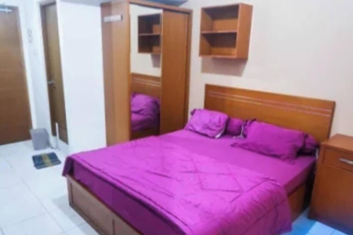 Een slaapkamer met een bed, een kledingkast en een nachtkastje.