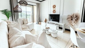 En moderne stue med sofa, sofabord, TV og spiseplads.