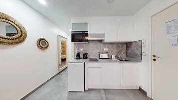 Una cocina moderna con armarios blancos, horno empotrado, cafetera y tostadora.