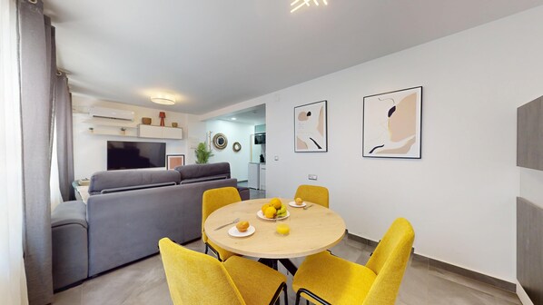 En moderne stue med en grå sofa, et spisebord med gule stole og kunst på væggene.