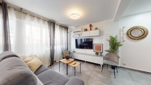 A modern living room with a grey sofa, a small coffee table, and a TV mounted on the wall. - MyFlats Premium Teatro (Alicante)