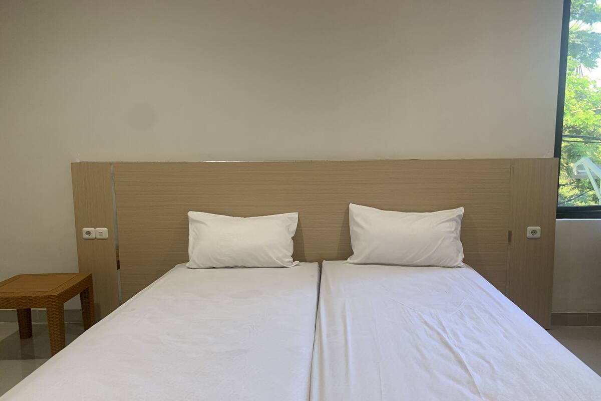 A double bed with white linens and a wooden headboard in a hotel room.