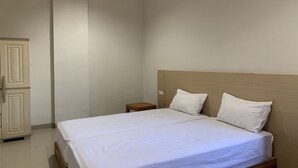 Ein ordentlich bezogenes Bett mit weißen Leinen und zwei Kissen in einem Zimmer, das ein Holz-Kopfteil und einen kleinen Nachttisch hat.