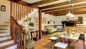 Ein geräumiger Wohnbereich mit einer Holztreppe, einem Kamin und einem für eine Mahlzeit gedecktem Esstisch.