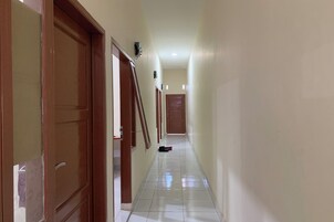 Un pasillo con puertas de madera y suelo de baldosas.