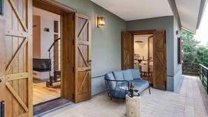 A cozy outdoor seating area with a sofa and a table, wooden doors leading to a staircase, and a view of the outdoors. - Charming house with terrace in Linguaglossa - DiCasaInSicilia (Linguaglossa)