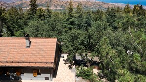 A building with a tiled roof and a view of a mountainous landscape with a body of water in the distance. - Charming house with terrace in Linguaglossa - DiCasaInSicilia (Linguaglossa)