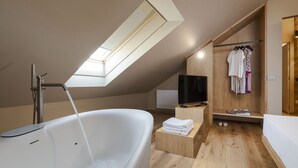 A modern bathroom with a skylight, a bathtub, a wooden vanity, and a television. - Charming house with terrace in Linguaglossa - DiCasaInSicilia (Linguaglossa)