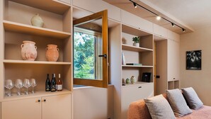 A modern room with built-in shelves, a bed with grey cushions, and a window with a view of greenery. - Charming house with terrace in Linguaglossa - DiCasaInSicilia (Linguaglossa)