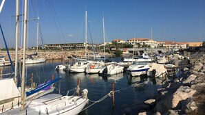A marina with various boats docked, a rocky shoreline, and a building with multiple balconies in the background. - T3 Apartment facing the sea with terrace and private parking in Sète (Sète)