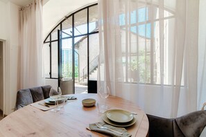 A dining area with a round table set for two, a bowl, wine glasses, and a plate. - One Love (Laglio)
