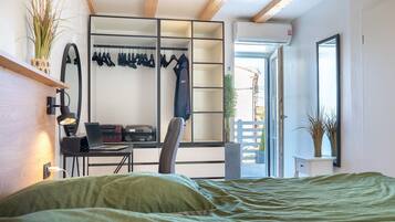 Une chambre à coucher avec un lit, un bureau avec un ordinateur portable, une chaise, une armoire et une fenêtre donnant sur un beau paysage.