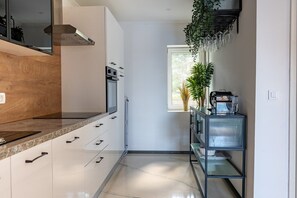 A modern kitchen with white cabinets, a stainless steel oven, and a black countertop.