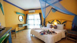 A hotel room with a bed, a nightstand, a dresser, a mirror, and a window with curtains. - BEACHCOMBER HOTEL AND RESORTS (Dar es Salaam)