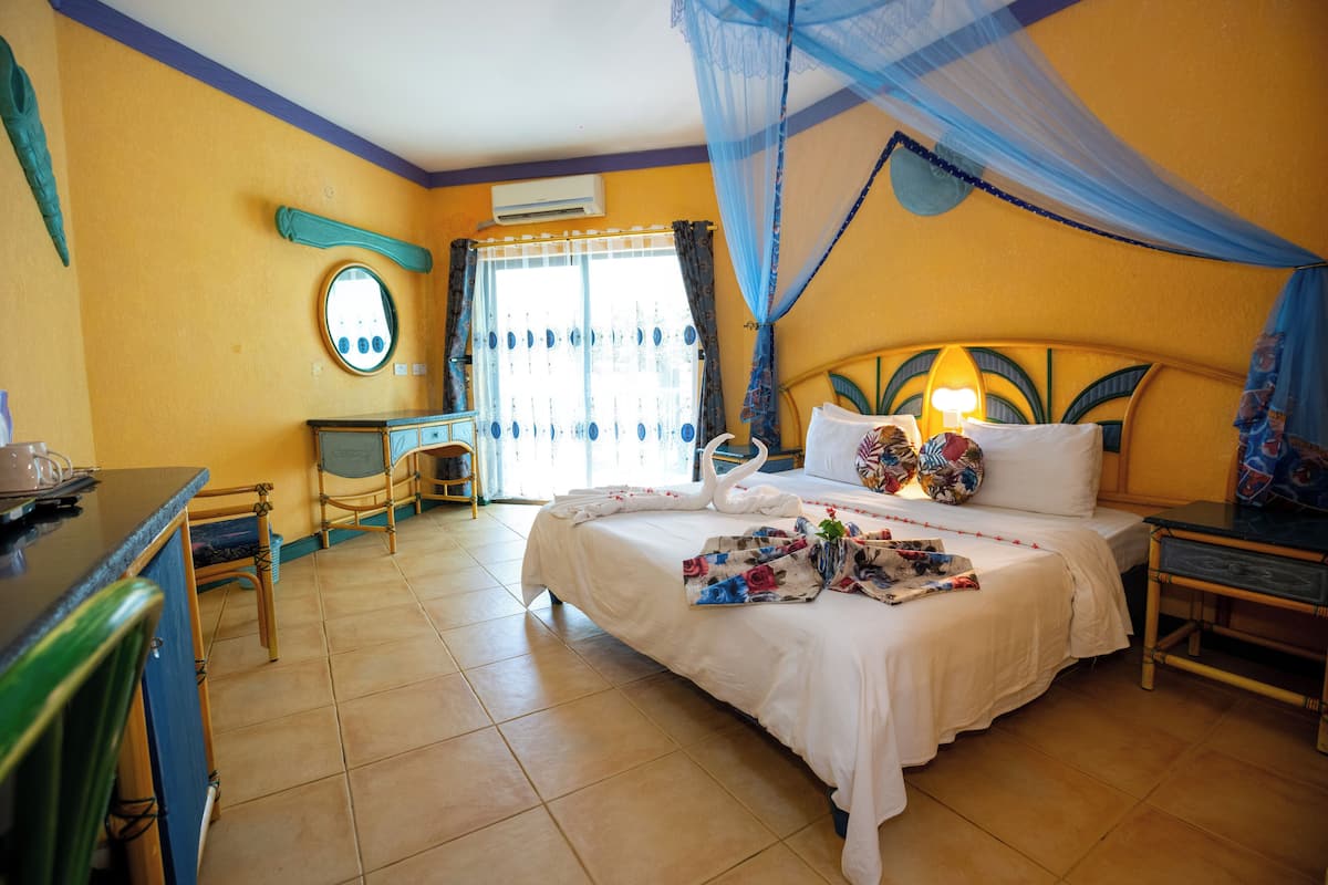 A hotel room with a bed, a nightstand, a dresser, a mirror, and a window with curtains.
