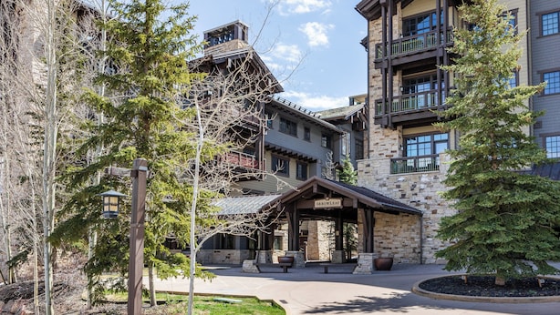 A building with a stone facade, multiple balconies, and a covered entrance area. - Deer Valley Luxury Residence: True Ski-in/ Ski-out, Cozy Interiors, Private Patio (Park City)