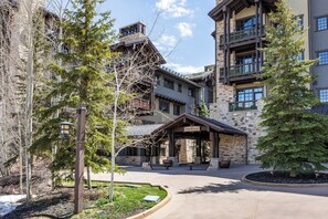 A building with a stone facade, multiple balconies, and a covered entrance area.