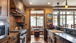 A modern kitchen with granite countertops, stainless steel appliances, and a large island with stools. - Deer Valley Luxury Residence: True Ski-in/ Ski-out, Cozy Interiors, Private Patio (Park City)