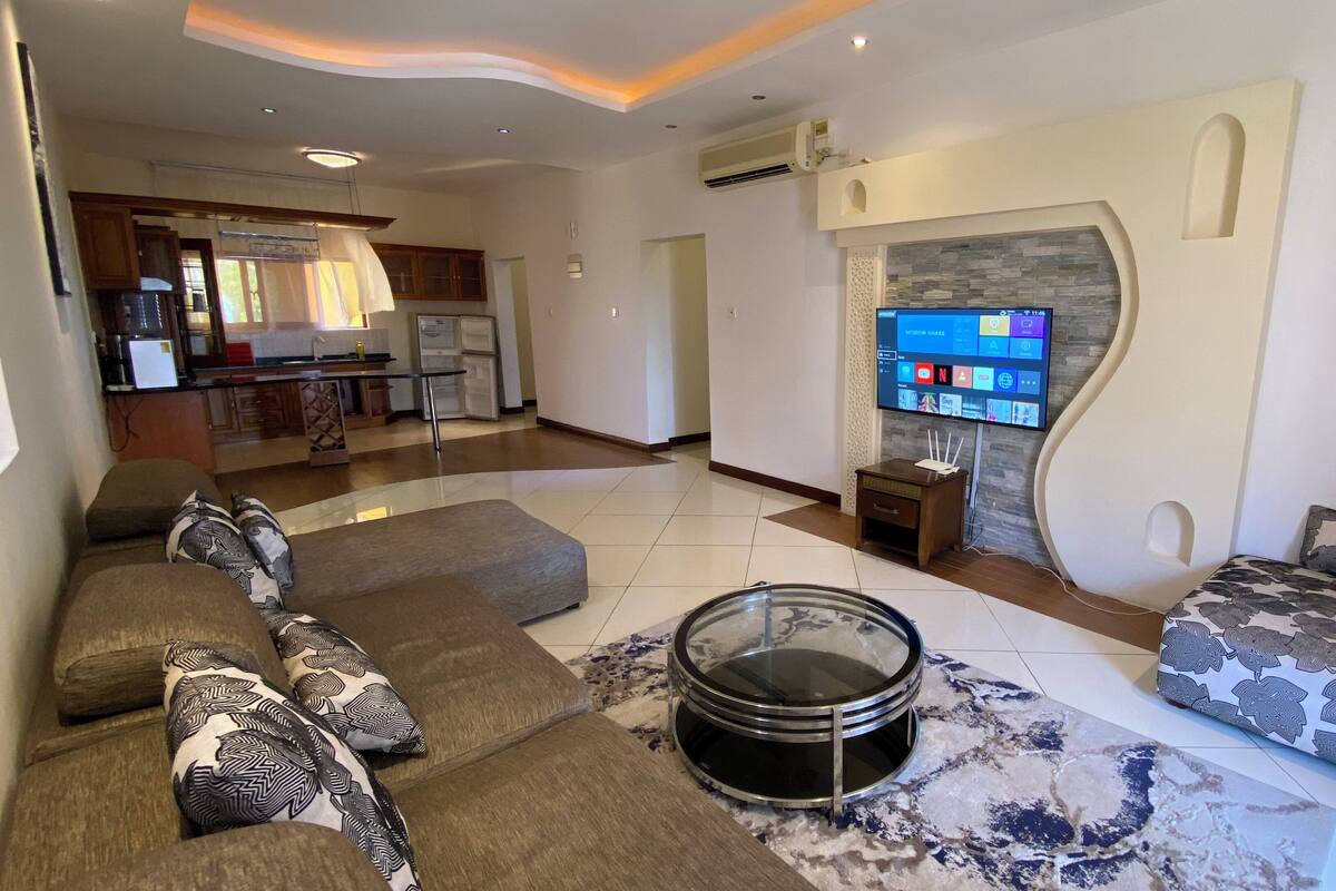 Een moderne woonkamer met een bank, een salontafel en een flatscreen televisie aan de muur.