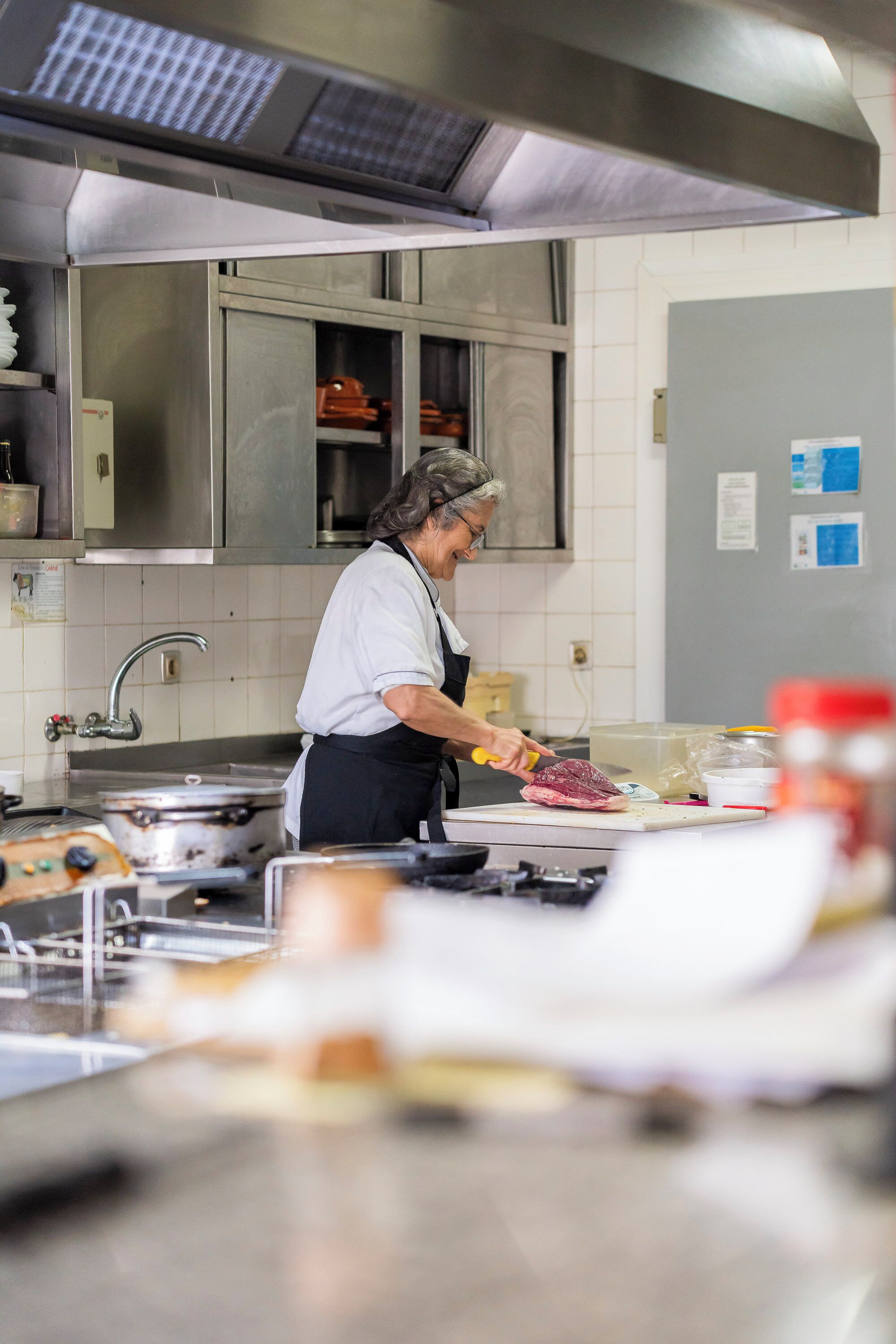 A kitchen with stainless steel appliances, a cutting board, and a person preparing food.