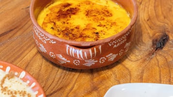 Un tazón de terracota con un plato cremoso, posiblemente un postre, sobre una mesa de madera.
