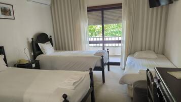 Een hotelkamer met twee enkele bedden, een bureau, een stoel, een telefoon en een raam met gordijnen.
